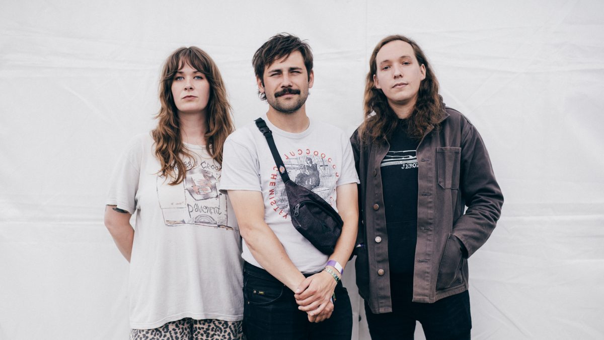 The three members of Other Half stand against a white wall.