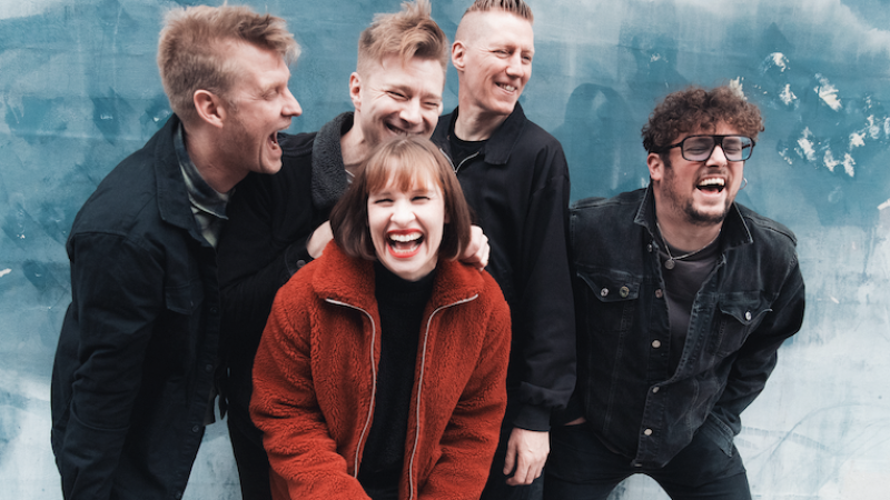 Four men and a women laughing in front of a sky blue background Four men and a women laughing in front of a sky blue background