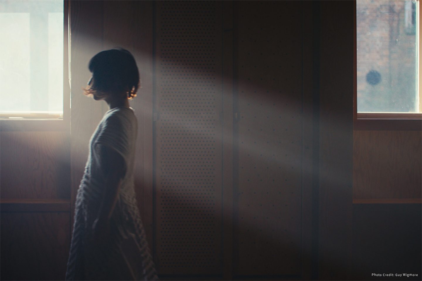 Figures in front of the light of the window. They are facing to one side and wearing a white dress.