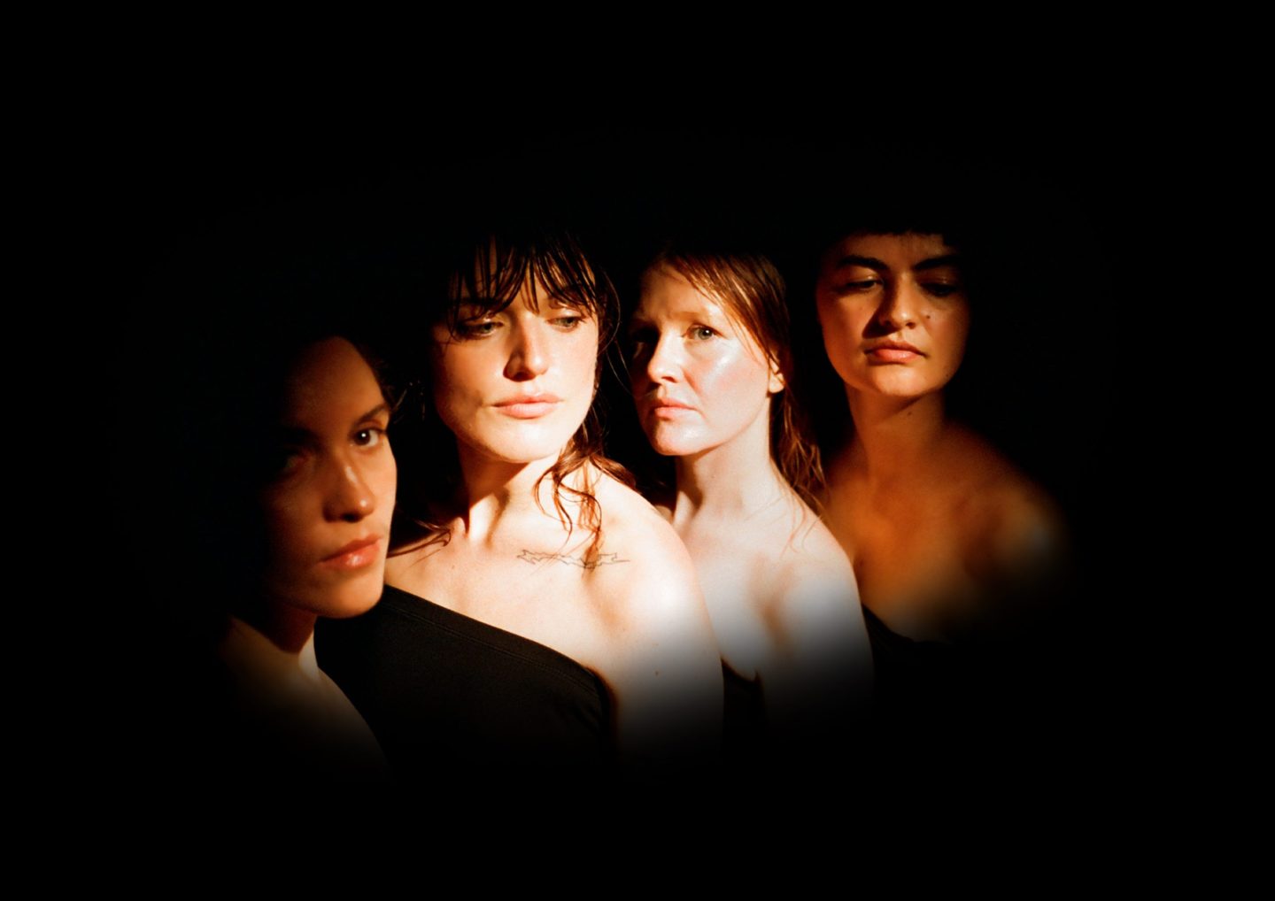 The lit-up face and shoulders of four people gathered together. The lit-up face and shoulders of four people gathered together.