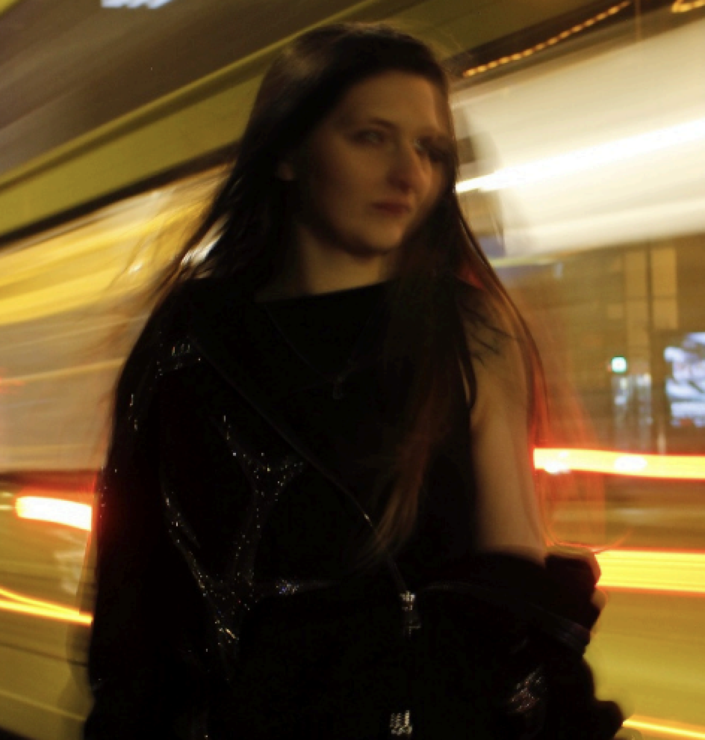 A person in dark clothing stands in front of a brightly lit, yellow vehicle in motion at night, with light trails creating a dynamic blurred background. A person in dark clothing stands in front of a brightly lit, yellow vehicle in motion at night, with light trails creating a dynamic blurred background.