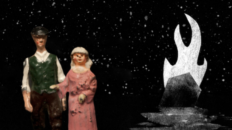 Two small figurines stand against a dark, starry background. One wears a green vest with dark trousers, the other a long pink dress. In the dista